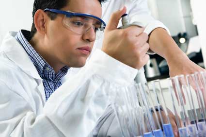 A laboratory scientist uses a pipette to transfer liquid.