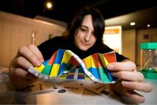 An individual holds a DNA model, with a concentrated face as if studying it.