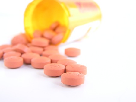 A prescription bottle lays on its side, with pills spilling out of its container