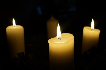 Three candles are lit in a darkened room.