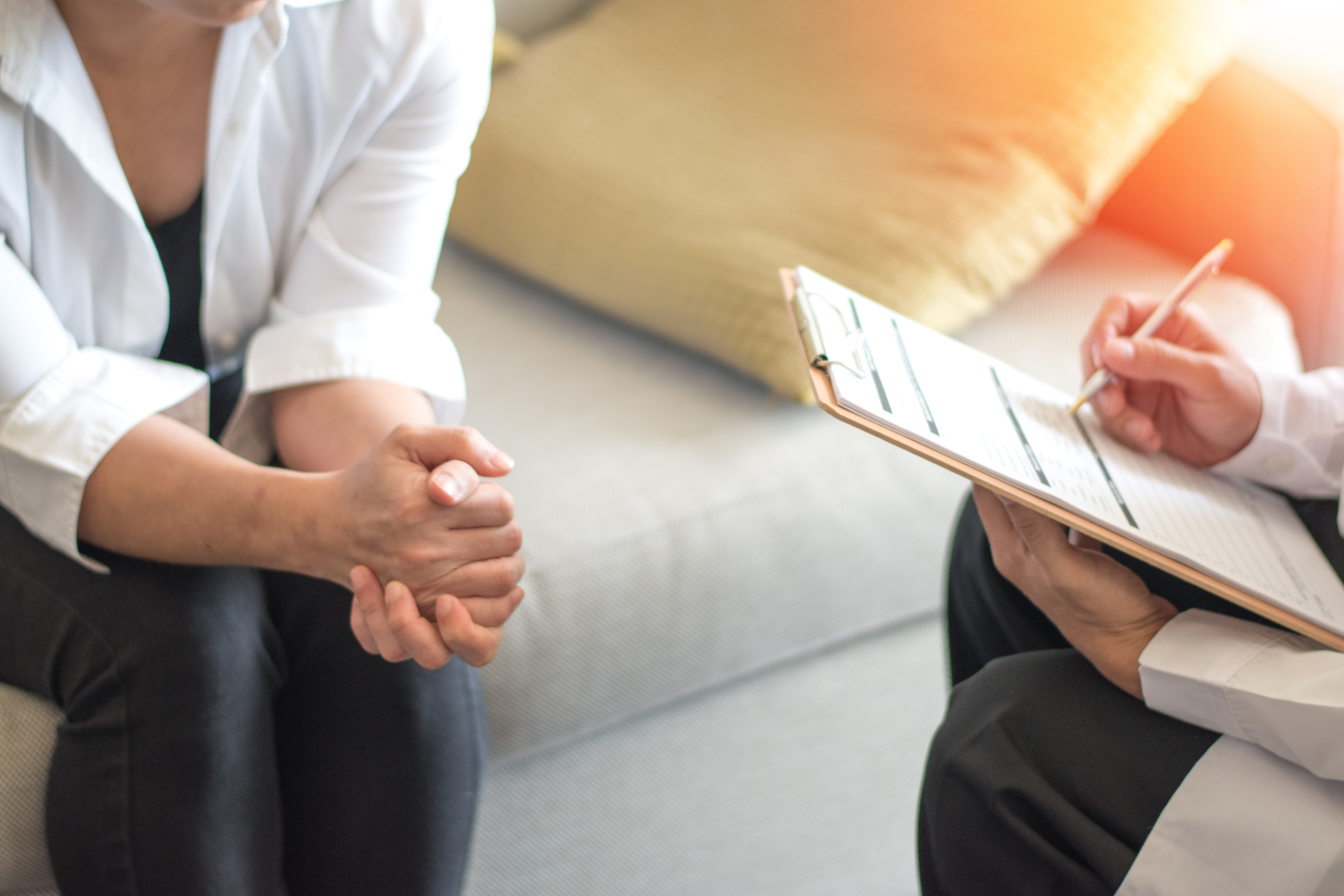 A doctor holding a clipboard goes over test results with a patient. Only their hands are shown. 