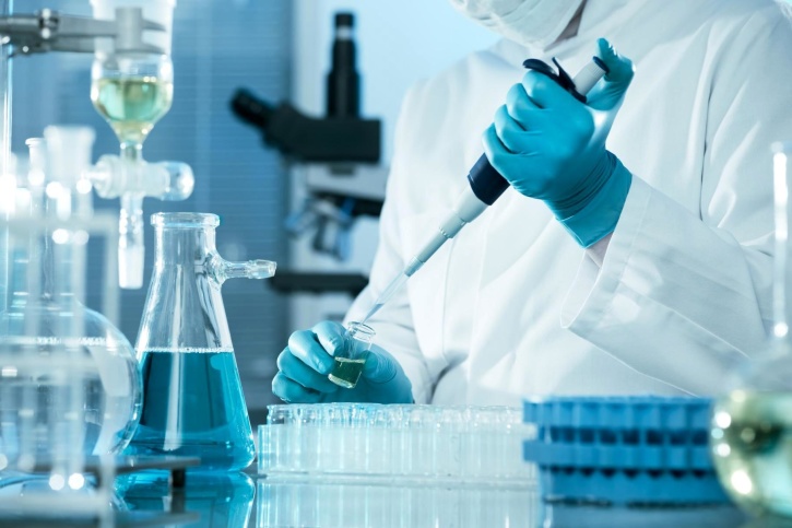 a person using a pipette with lab equipment around them