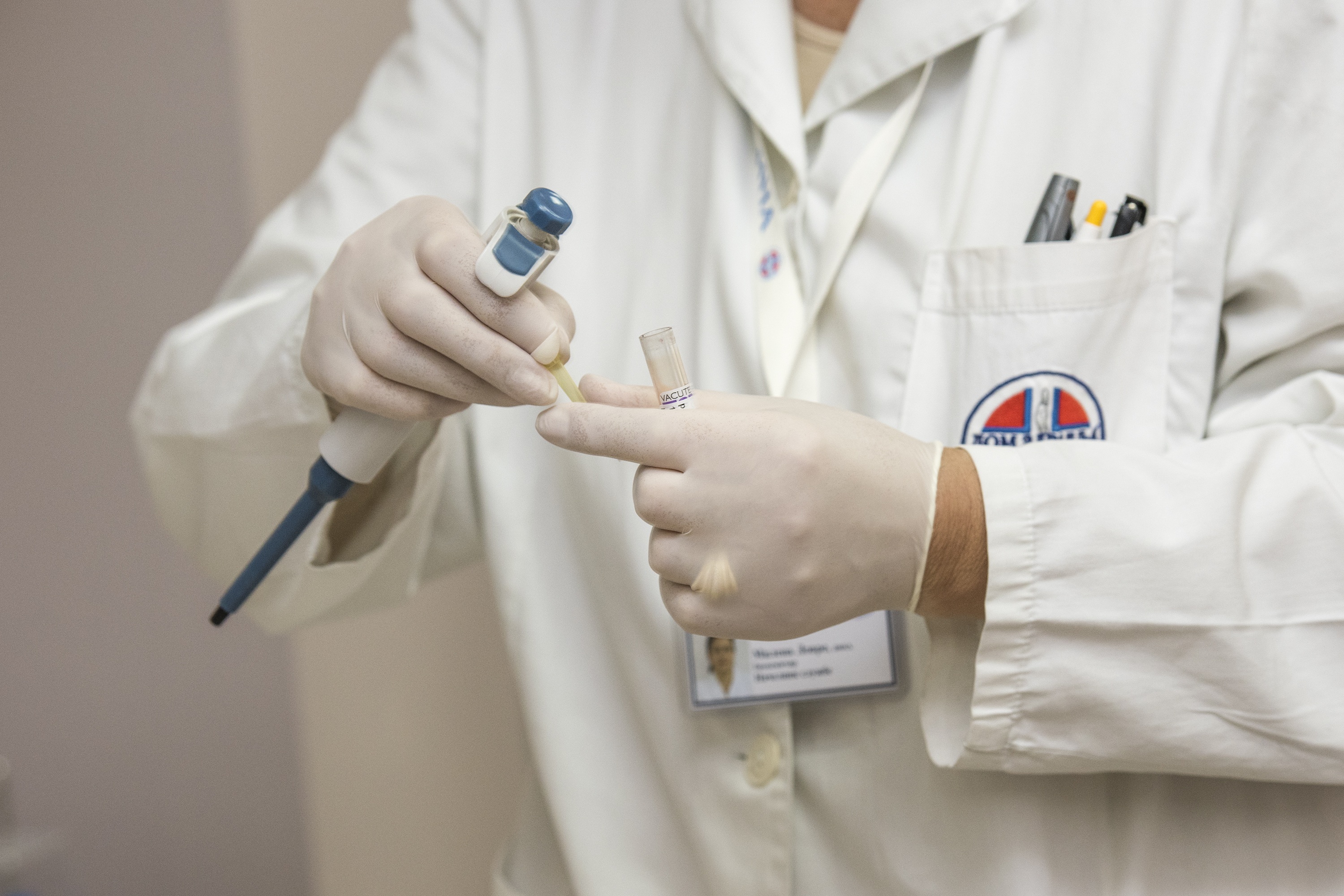 Close up of a person in a white lab coat holding a test tube.