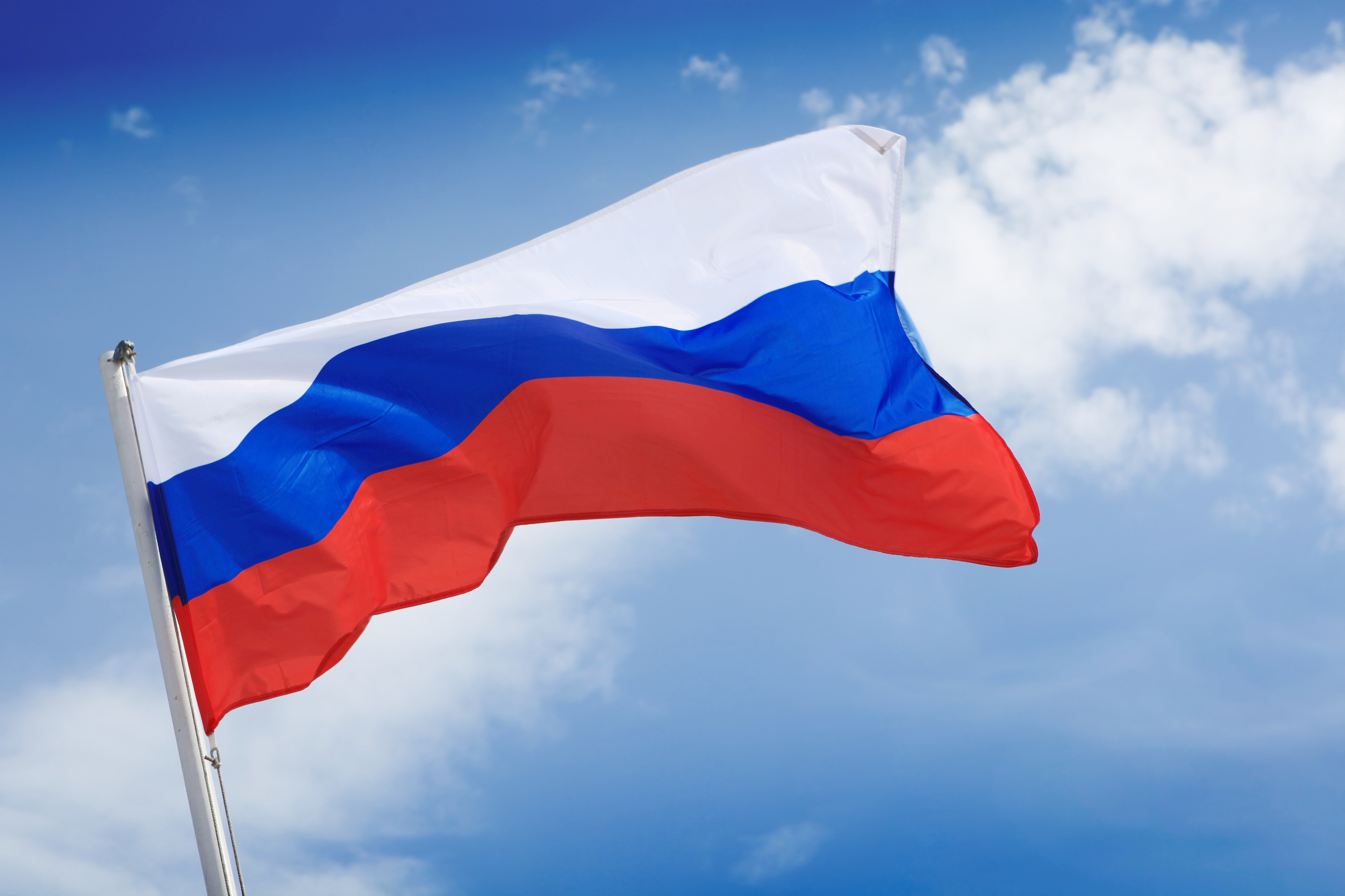 Photo of the Russian flag and a blue sky with clouds