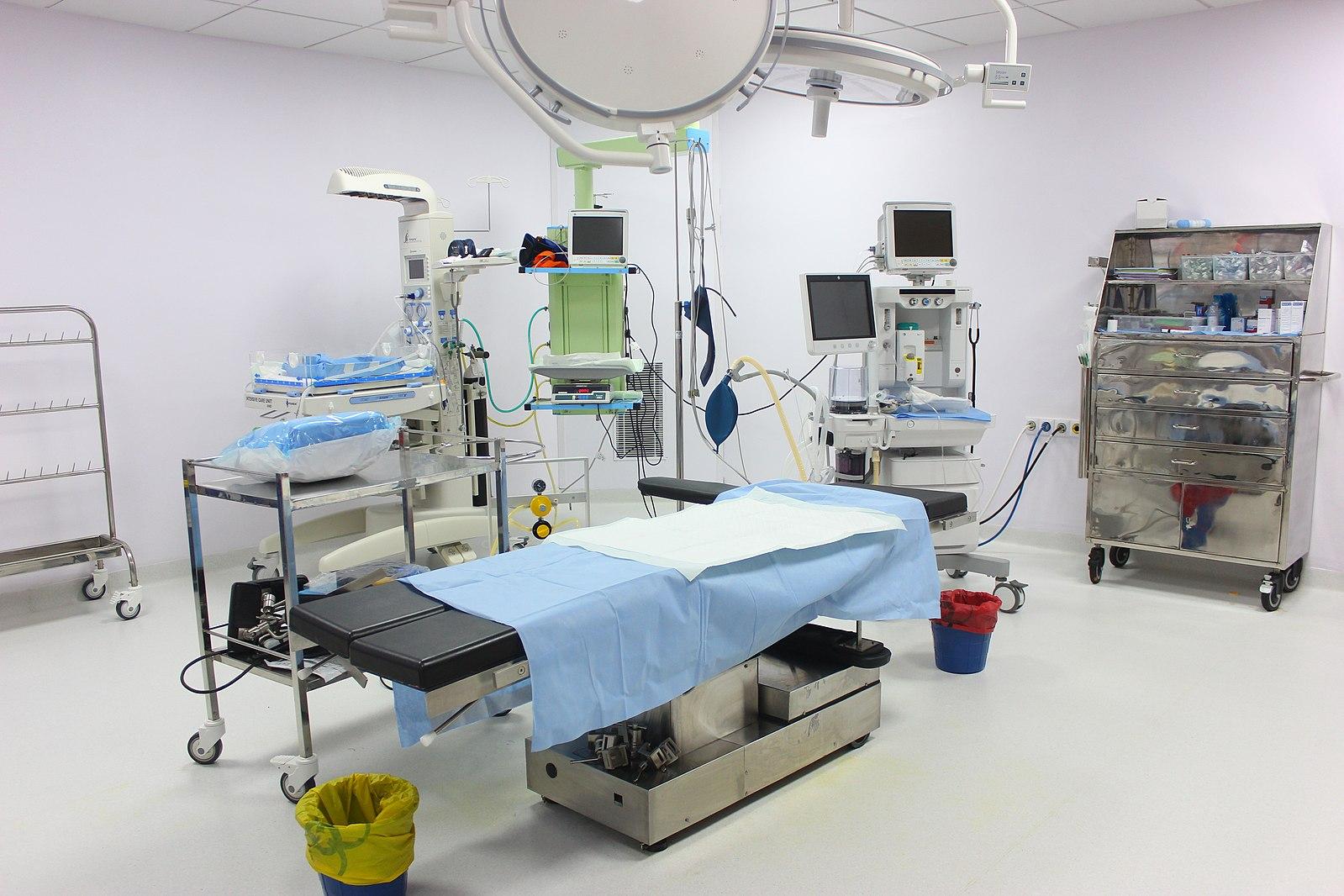 Blue operating table surrounded by other surgical equipment