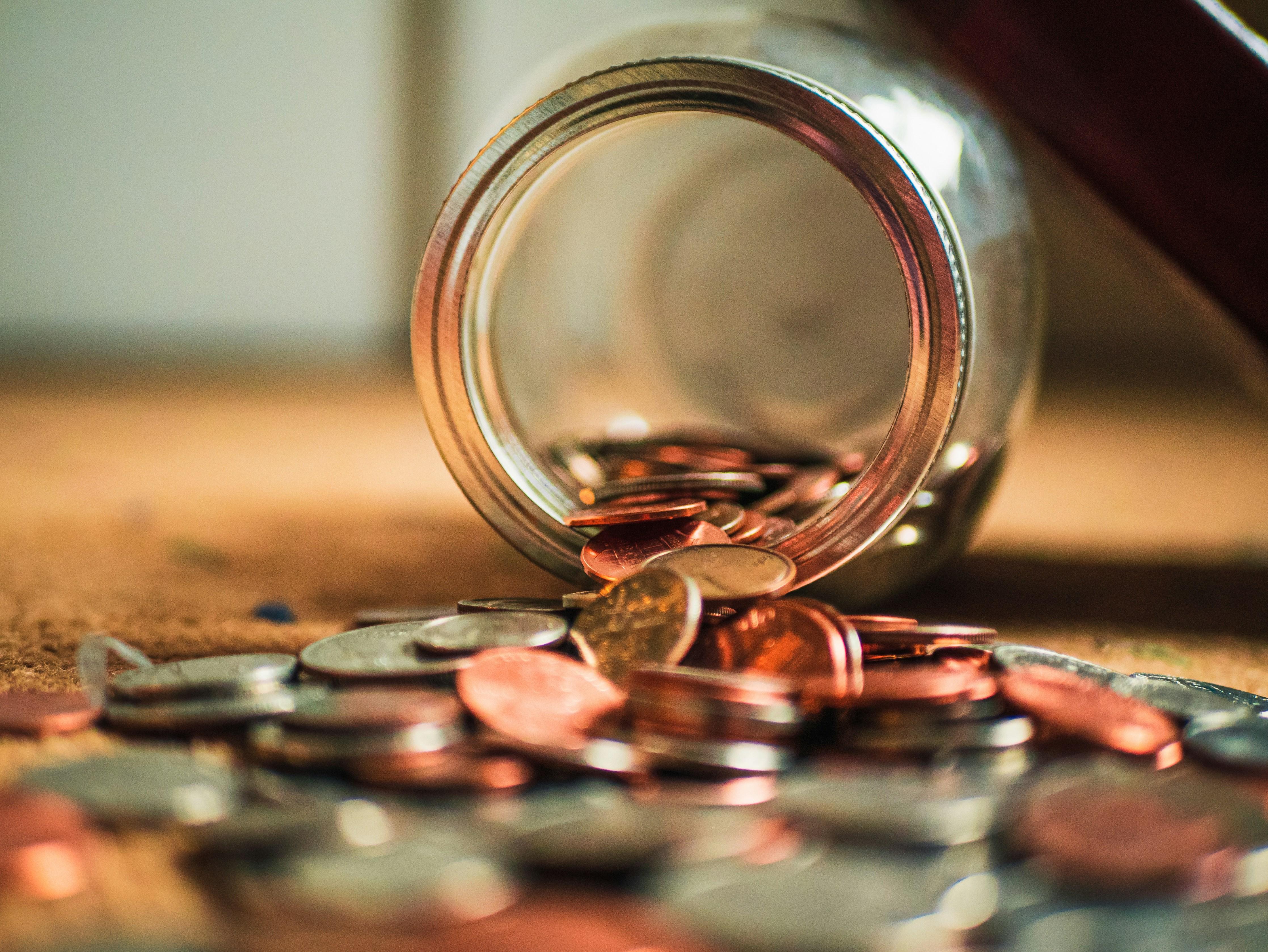 Image of coins spilling from glass jar