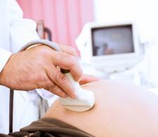 A doctor uses a plastic transducer for an ultrasound of patient's uterus. 