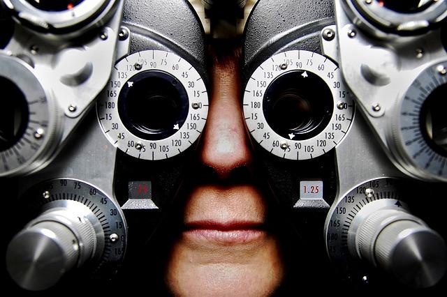 A patient looks through an eye doctor's instrument, which covers their face almost completely.