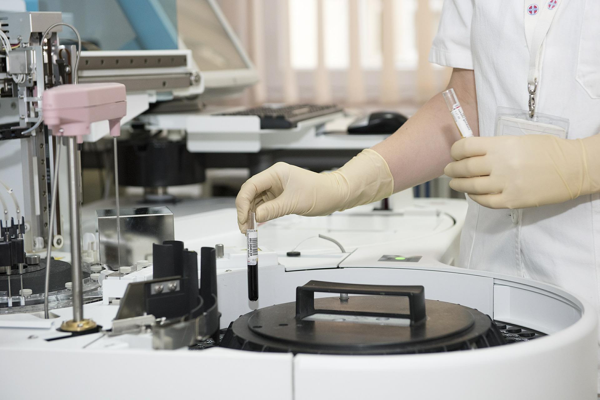 a person with gloves in a lab setting holding a test tube.