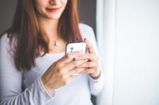 A woman is looking at her smart mobile phone.