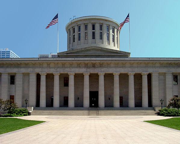 Front of Ohio State House. Lawn, building, and two American flags.