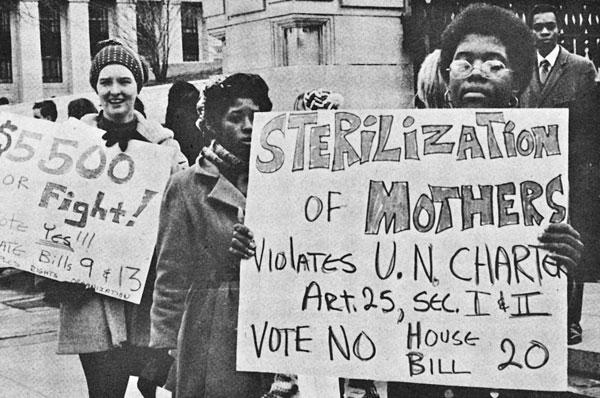 A female, African American protester holds a sign that reads, "Sterilization of mothers violates U.N. charter. Vote No on House Bill 20."