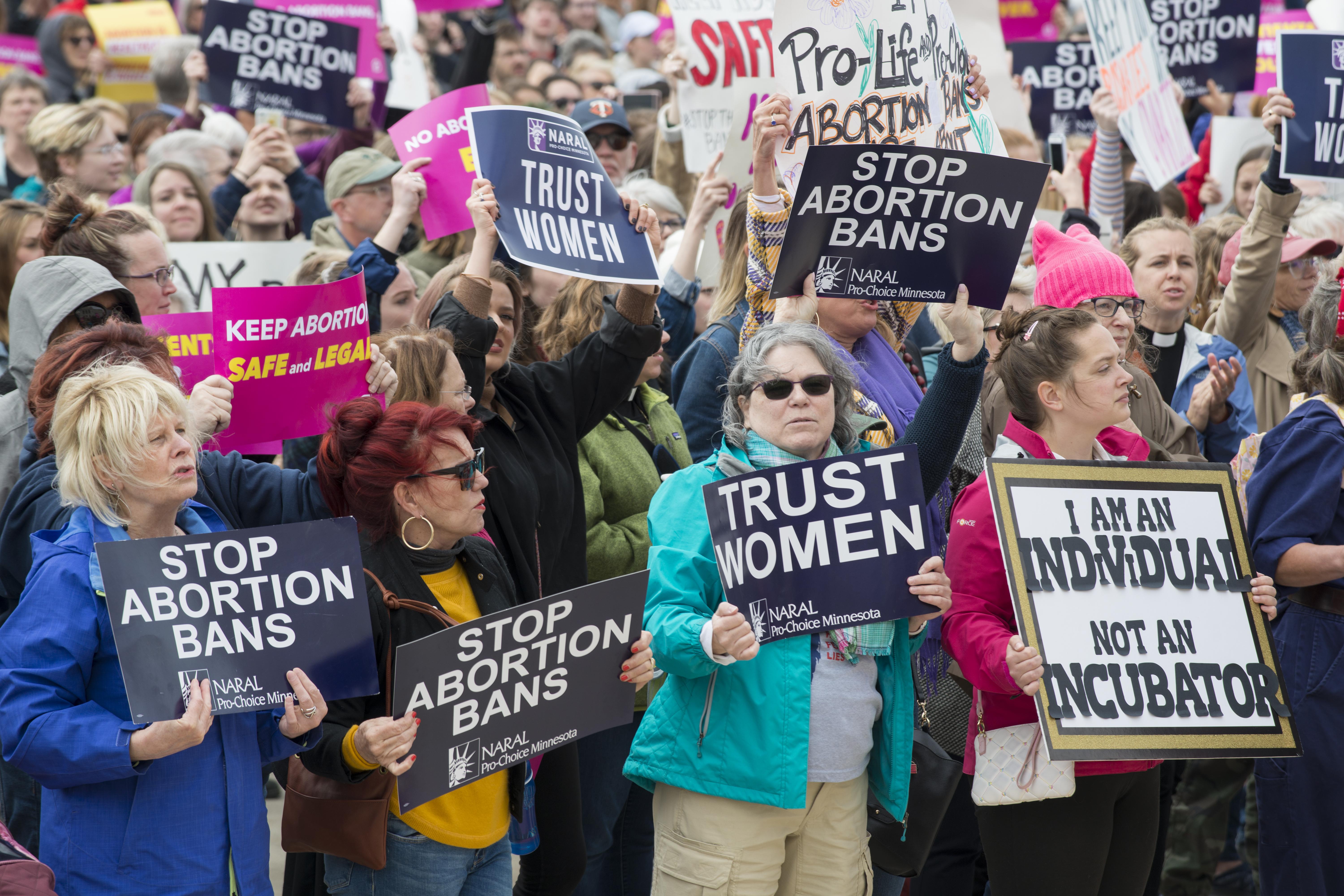 Women protesting with signs that read "stop abortion bans"