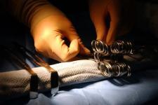 A surgeon's hands hold sterilized tools under a light.